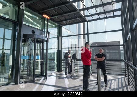 Arnavutkoy, Istanbul, Türkei - 03.08.2021: Raucherlounge am Flughafen Istanbul und einige Leute mit Maske rauchen Zigaretten vor Aschenbechern im Tagesli Stockfoto