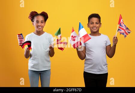 Glückliche schwarze Kinder posieren mit verschiedenen Fahnen Stockfoto