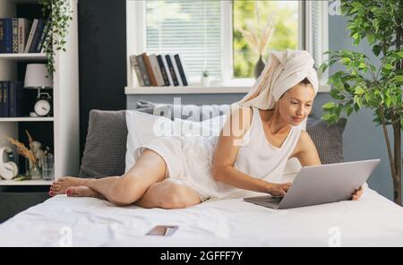 Frau im Bett mit laptop Stockfoto