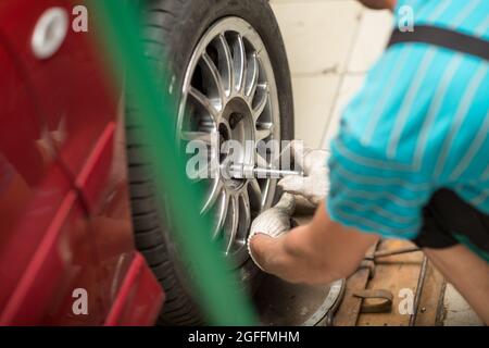Reparatur oder Austausch von Reifen Kfz-Mechaniker Schrauben Autorad an der Reparatur-Service-Station. Stockfoto