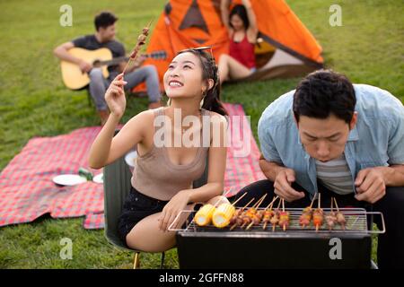 Glückliche junge Freunde grillen draußen Stockfoto