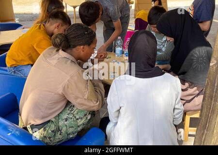 Ein Seemann der United States Navy und afghanische Kinder, die evakuiert wurden, stellten Puzzles auf der Naval Air Station Sigonella zusammen, 24. August 2021. NAS Sigonella unterstützt die Mission “Operation Allies Refuge des Verteidigungsministeriums, um die sichere Ausreise und Umsiedlung von US-Bürgern, Empfängern von Sondervisa für Immigration und gefährdeten afghanischen Bevölkerungen aus Afghanistan zu erleichtern. Obligatorische Gutschrift: Kevin Pickard, Jr./US Navy über CNP Stockfoto