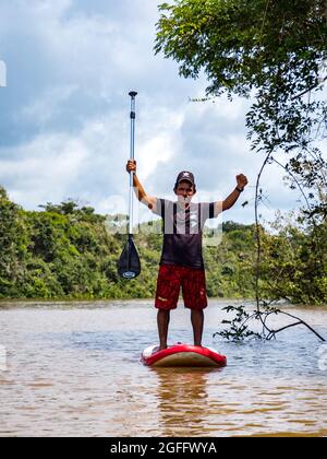 Laguna Onza, Brasilien - Dez 2019: Porträt eines Mannes, der auf einem aufblasbaren Brett auf dem Wasser schwimmt, Bewohner des Amazonas-Regenwaldes. Amazonien. Lateinamerikanisch Stockfoto