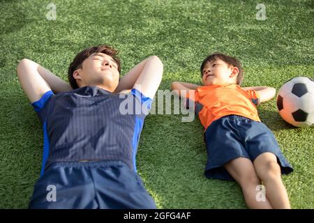 Vater und Sohn liegen auf dem Fußballplatz Stockfoto