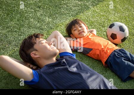 Vater und Sohn liegen auf dem Fußballplatz Stockfoto