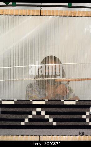 Eine indianische Frau aus Navajo demonstriert die Kunst, einen Teppich auf einem kleinen Webstuhl zu weben, auf dem jährlichen Santa Fe Indian Art Market in New Mexico. Stockfoto