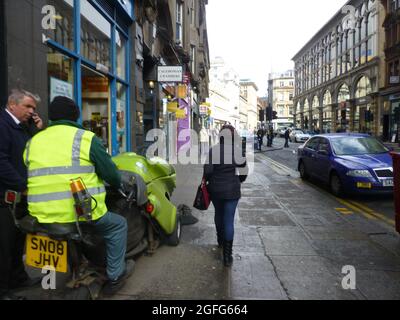 Straßenreiniger in Glasgow Schottland Arbeitsarbeiter Reinigungsmaschinen Reinigungsmaschine nasses Wetter Menschen Schild Hut kalt nass überdachte Straßen Straße Straßenpflaster Straße Stockfoto