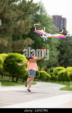 Kleines Mädchen, das Drachen im Park fliegt Stockfoto