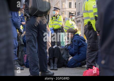 Oxford Circus, London, Großbritannien. August 2021. Die Protestierenden der „Extinction Rebellion“ besetzen den Oxford Circus bei der „Impossible Rebellion“. Starke Polizeipräsenz, die Frau wurde an der Kreuzung des oxford Circus zwischen Regent Street und Oxford Street mit einer Kette an Boden gekettet, an der Spezialpolizei teilnahm, die versuchte, sie freizuschneiden. Quelle: Xiu Bao/Alamy Live News Stockfoto