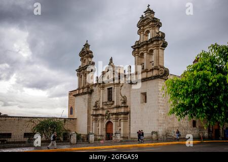 Cajamarca, Cajamarca/Peru - 16.12.2019: Peruanische Einheimische kommen an einem regnerischen Tag an der Kirche und dem Kloster La Recoleta in Cajamarca, Peru vorbei Stockfoto