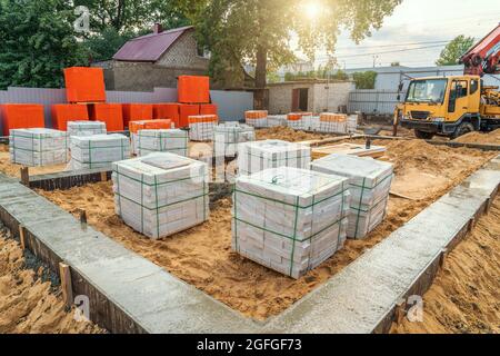 Frisch gegossenes Streifenfundament auf der Baustelle und Baustoffe für den Neubau. Stockfoto