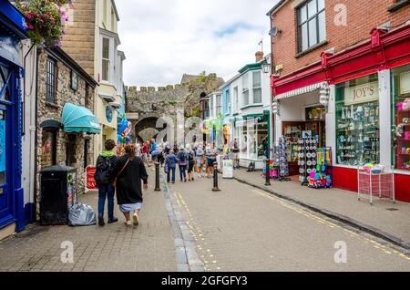 Blick auf die St George Street in Tenby, Wales, mit Blick auf das Tor der fünf Bögen. Die Straße ist voller Touristen und mit Souvenirläden gesäumt. Stockfoto