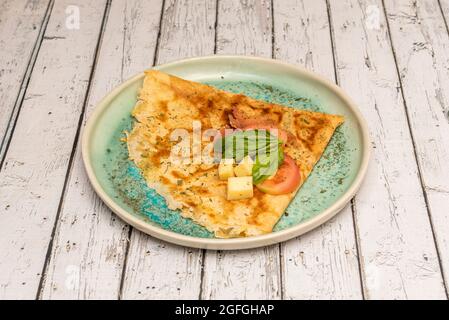 Salziges Crepe mit serrano-Schinken mit Käse, Tomaten und Basilikum auf einem blauen Teller Stockfoto