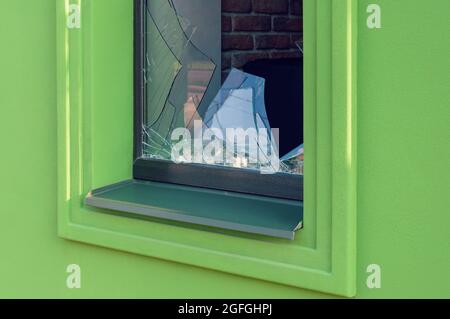Gebrochenes grünes Glasfenster an der Fassade in Nahaufnahme Stockfoto