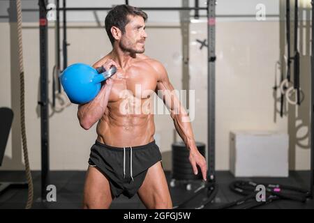 Schöner muskulöser Mann, der schwere Kugelhantel hebt. Hochwertige Fotos. Stockfoto