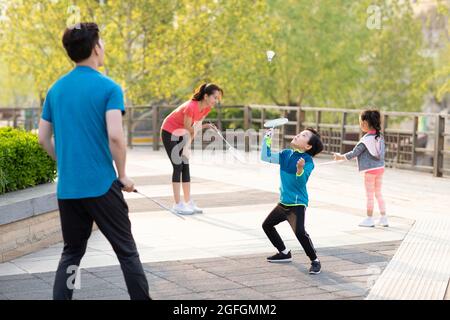 Glückliche junge Familie spielt Badminton im Park Stockfoto