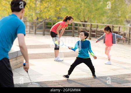 Glückliche junge Familie spielt Badminton im Park Stockfoto