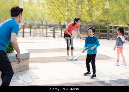 Glückliche junge Familie spielt Badminton im Park Stockfoto