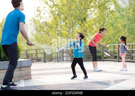 Glückliche junge Familie spielt Badminton im Park Stockfoto