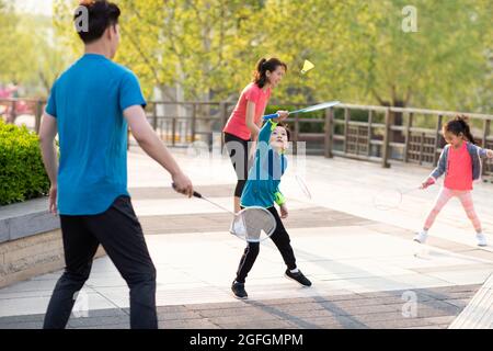 Glückliche junge Familie spielt Badminton im Park Stockfoto