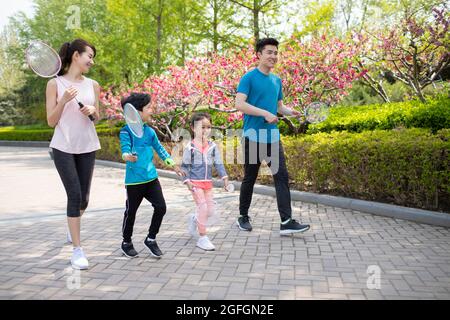 Glückliche junge Familie spielt Badminton im Park Stockfoto