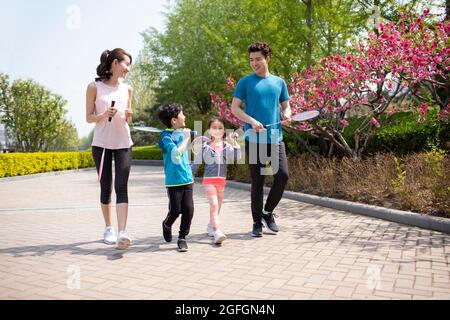 Glückliche junge Familie spielt Badminton im Park Stockfoto