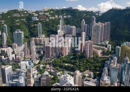 Die Hochhäuser mit Wohnhäusern in den mittleren Etagen und Luxushäusern auf dem Peak über den Geschäftsgebäuden von Central, Hong Kong Island Stockfoto