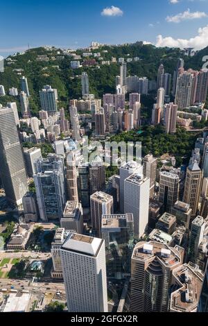 Die Hochhäuser mit Wohnhäusern in den mittleren Etagen und Luxushäusern auf dem Peak hinter den Geschäftsgebäuden von Central, Hong Kong Island Stockfoto