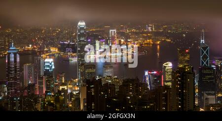 Das Hochhaus von Central auf Hong Kong Island und Tsim Sha Tsui, Kowloon bei Nacht mit Rauch vom Feuerwerk zur Feier des chinesischen Neujahrs Stockfoto