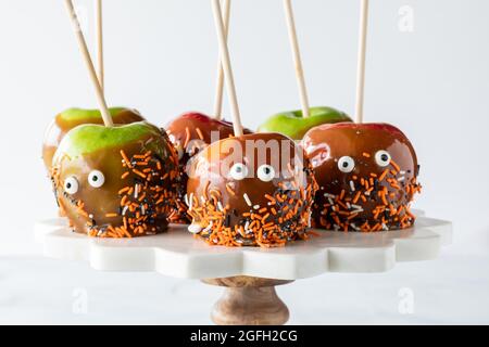 Karamelläpfel für Halloween, auf einem Standfuß, vor einem hellen Hintergrund. Stockfoto