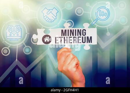 Schild mit dem Mining Ethereum. Wort geschrieben über den Prozess der Erhöhung des Volumens von Äther in Umlauf Hand halten Puzzle Stück Stockfoto