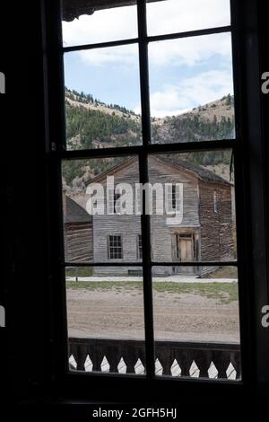 Gebäude durch Fenster auf der anderen Straßenseite, Bannack State Park, MT. Stockfoto