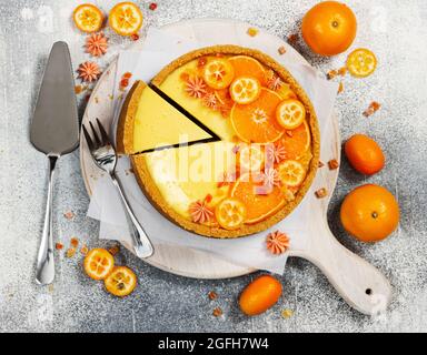 Käsekuchen mit Orangenscheiben und Kumquat auf grauem Steingrund. Draufsicht. Stockfoto