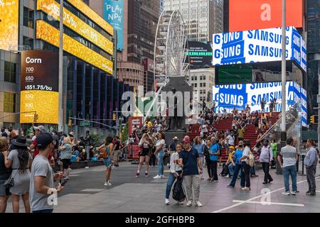 NEW YORK, NY - 25. AUGUST: Am 25. August 2021 versammeln sich die Menschen auf dem Times Square mit dem Riesenrad als Kulisse in New York City. Das 110 Meter lange Times Square-Riesenrad, das sich am Broadway zwischen der 47. Und der 48th Street befindet, ist bis zum 14. September 2021 geöffnet. Kredit: Ron Adar/Alamy Live Nachrichten Stockfoto