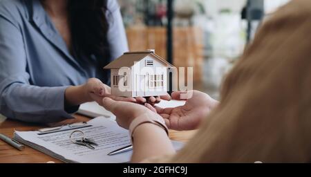 Immobilienmakler oder Verkaufsleiter bieten Hausverkauf und erklärte die Bedingungen der Unterzeichnung des Hauskaufvertrags und kostenlose Hausversicherung. Hypothek Stockfoto