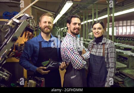 Porträt von glücklichen jungen Arbeitern in der Schuhfabrik, die in der Montagehalle stehen Stockfoto