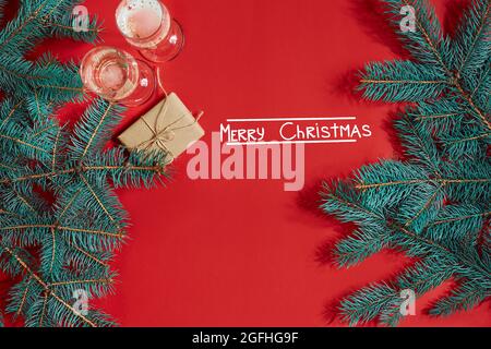 Zwei Gläser Champagner mit Christbaumzweig und kleinem Geschenk auf rotem Hintergrund Stockfoto