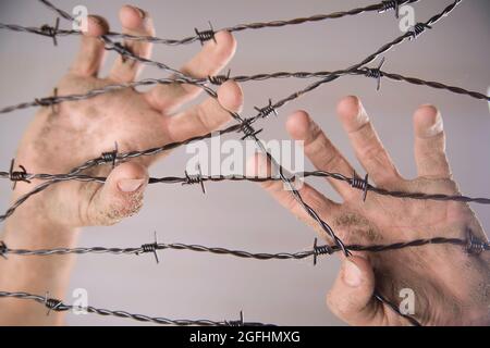 Hände greifen der Stacheldraht im Zeichen weg mit dem weißen Hintergrund zu laufen Stockfoto