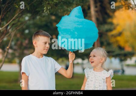 Glückliche Kinder Junge und Mädchen essen blaue Zuckerwatte im Freien. Stockfoto