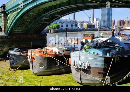 Bunte Lastkähne (heute Hausboote) unter dem Bogen der Battersea Railway Bridge über die Themse in London, England Stockfoto