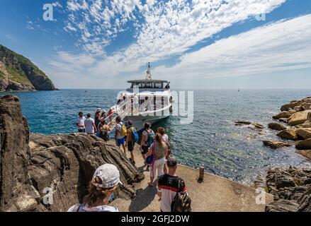 Fähre mit Touristen dockte vor dem kleinen Dorf Riomaggiore, Cinque Terre Nationalpark in Ligurien, La Spezia, Italien, Europa. Stockfoto