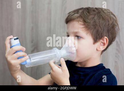 Kind Junge mit medizinischen Spray für den Atem. Inhalator, Abstandshalter und Maske. Seitenansicht Stockfoto