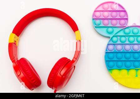 Trendy Silikon sensorische Spielzeug Antistress Pop it. Regenbogen Anti Stress Spielzeug Fidget und Kopfhörer auf weißem Hintergrund. Stockfoto