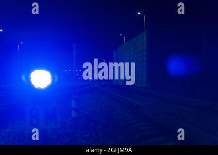 Die blaue Ampel am Nachtbahnhof leuchtet blau. In der Ferne Dunst und leuchtende Laternen. In der Nähe der Eisenbahn.verschwommener Vordergrund.Auswählen Stockfoto