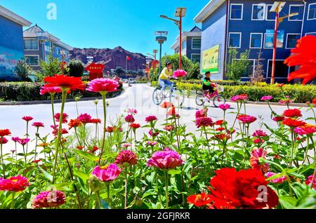 Linze, Linze, China. August 2021. Am 24. August 2021 können Sie das neue Dorf Liyuan, die Stadt Nijiaying, Bezirk Linze, Stadt Zhangye, Provinz Gansu, unter dem Berg Danxia aus birdÃ¢â‚¬â„¢-Sicht betrachten. Nach der Blüte der Blumen, kleinen Brücken und fließendem Wasser, Menschen im kleinen Hof, eine großartige neue ländliche Szene. In den letzten Jahren hat der Landkreis Linze, Stadt Zhangye, Provinz Gansu, eine abfallfreie Bewirtschaftung mit dem Bau schöner Dörfer und der Förderung der ländlichen Revitalisierung integriert. Die ganze Bevölkerung hat sich an den Bemühungen zur Verbesserung der ländlichen Umwelt beteiligt und eine Numbe geschaffen Stockfoto