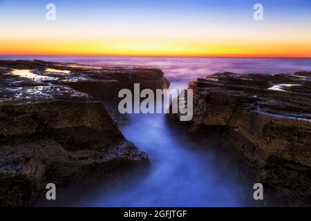 Zerklüftete Felsen am Narrabeen-Strand von Australien Sydney Nordstrände bei Sonnenaufgang - Sonnenaufgang über dem Pazifischen Ozean. Stockfoto