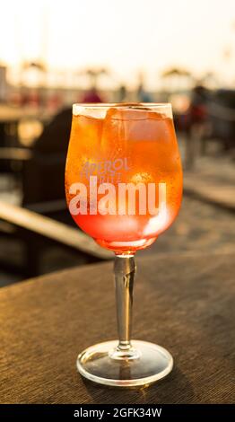 Nazare, Portugal - 18. August 2021: Aperol Spritz Cocktail auf einer Strandpromenade bei Sonnenuntergang Stockfoto
