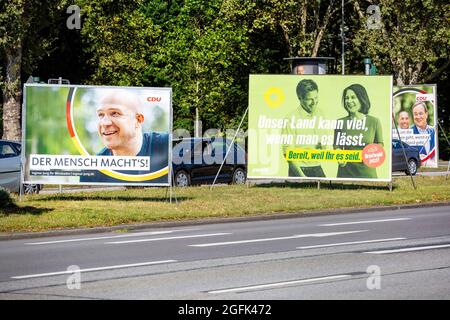 Wiesbaden, 25. August 2021: Wahlkampfplakate der Partei DIE GRÜNEN und der Christlich-Demokratischen Union (CDU) in der Innenstadt von Wiesbaden, Hessen. Deutschland steht am 26. September vor Bundestagswahlen. Einige Verkehrsteilnehmer im Hintergrund Stockfoto