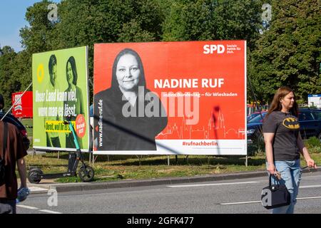 Wiesbaden, Deutschland - 25. August 2021: Wahlkampfplakate der Partei DIE GRÜNEN und der Sozialdemokratischen Partei (SPD) in der Innenstadt von Wiesbaden, Hessen. Deutschland steht am 26. September vor Bundestagswahlen. Einige Verkehrsteilnehmer im Hintergrund Stockfoto