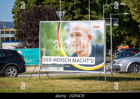 Wiesbaden, Deutschland - 25. August 2021: Wahlkampfplakat der Christlich Demokratische Union (CDU) in der Innenstadt von Wiesbaden, Hessen. Die Christlich-Demokratische Union (CDU) ist eine christdemokratische und liberal-konservative Partei in Deutschland und wird von Armin Laschet angeführt. Deutschland steht am 26. September vor Bundestagswahlen. Einige Verkehrsteilnehmer im Hintergrund Stockfoto